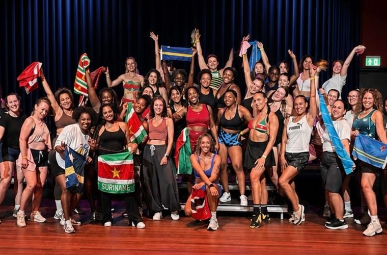 Groep deelnemers doet dansbewegingen tijdens een soca-fitnesssessie in de Spinozafoyer.